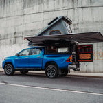 Tailgate Gear indretning til Alu-Cab ModCap & Canopy Camper – Toyota Hilux Double Cab (2015+) / Sort Raptor-birk & sølvfarvet struktur