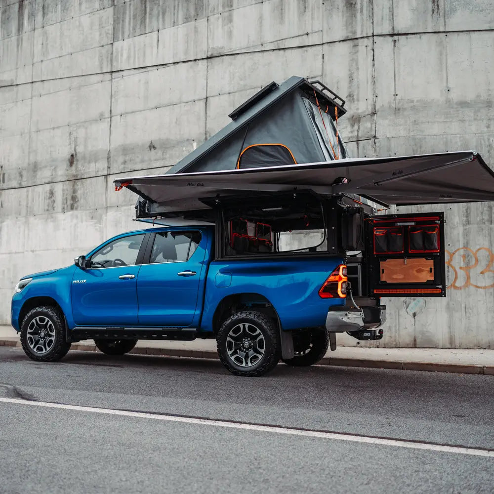 Tailgate Gear indretning til Alu-Cab ModCap & Canopy Camper – Toyota Hilux Double Cab (2015+) / Sort Raptor-birk & sølvfarvet struktur